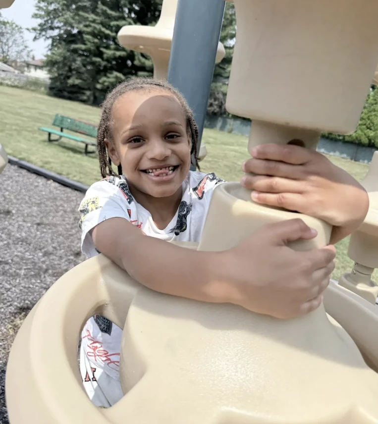 A smiling student plays on the playground