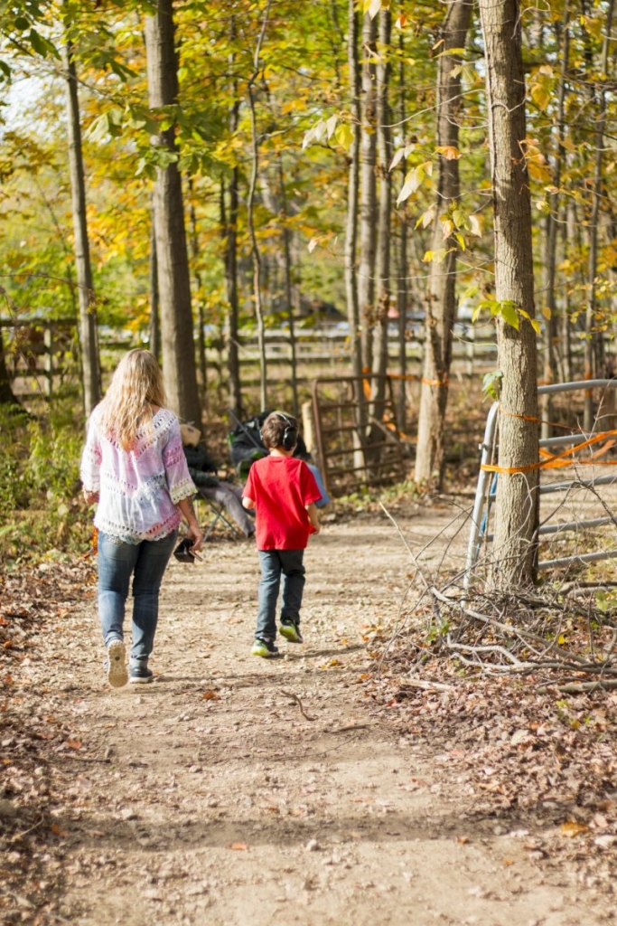 A child and an adult walking a wooded trail in autumn